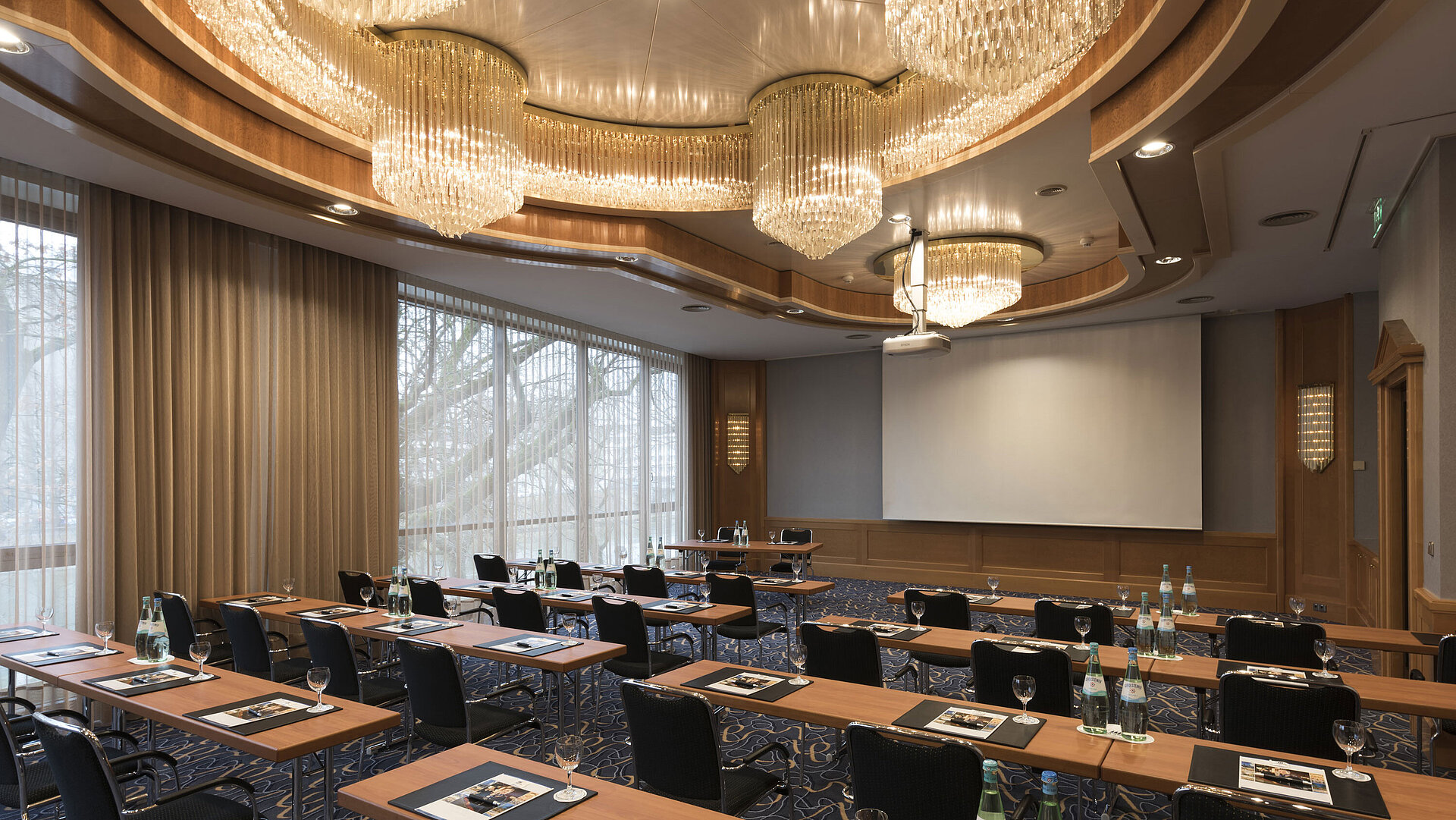 Salle de conférence élégante avec rangées de sièges, lustres et écran au Maritim Hotel Ulm.