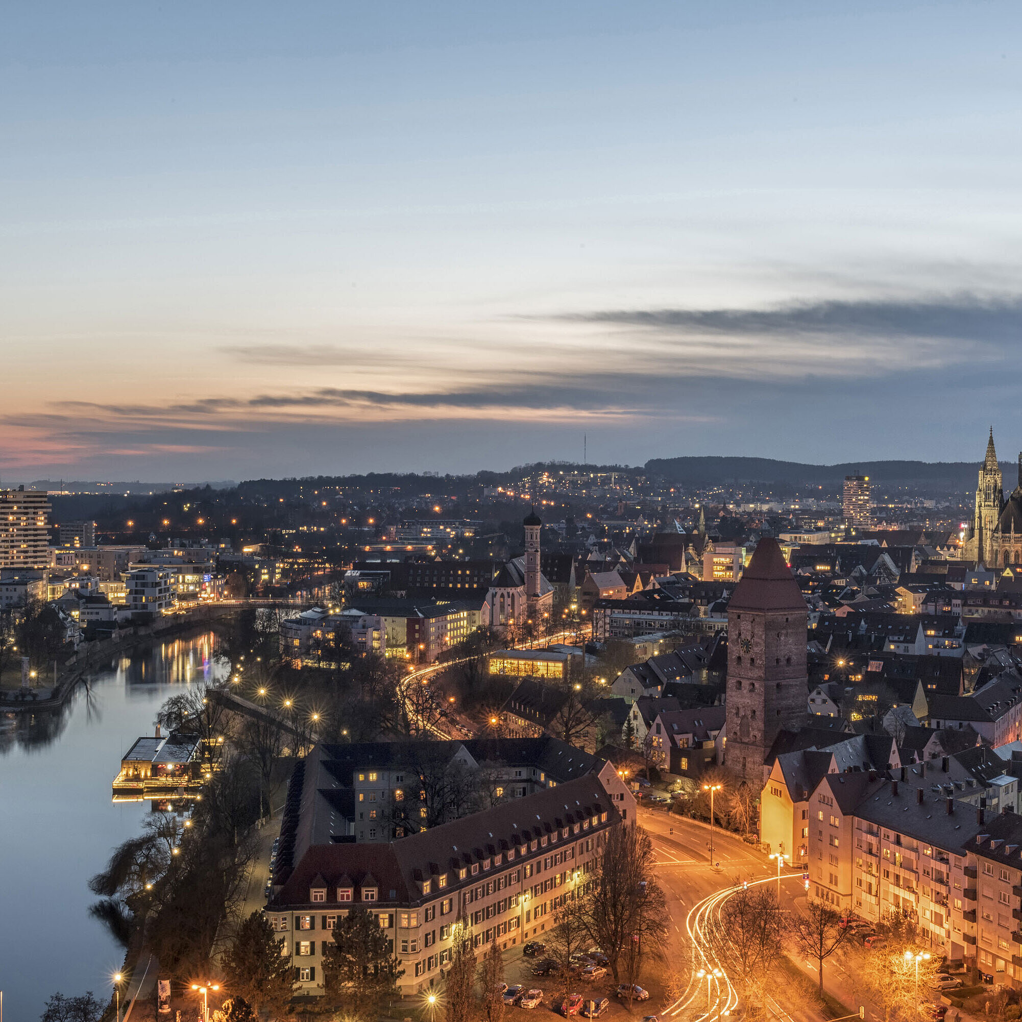 Night panorama of Ulm with illuminated Minster and Danube, captured at blue hour.