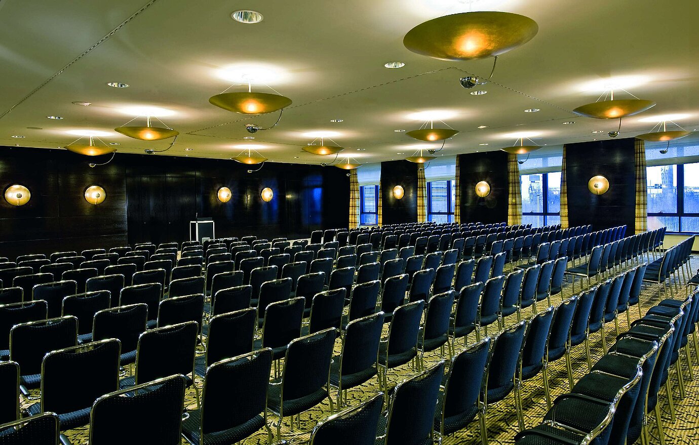 Conference room at Maritim Hotel Düsseldorf with elegant lighting and row seating, perfect for meetings and events.