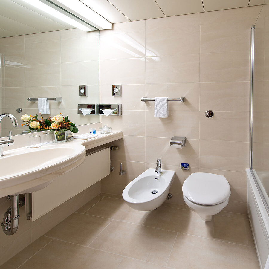 Bathroom Bright, elegant bathroom with bathtub, shower, sink, and mirror at Maritim Hotel Hannover.