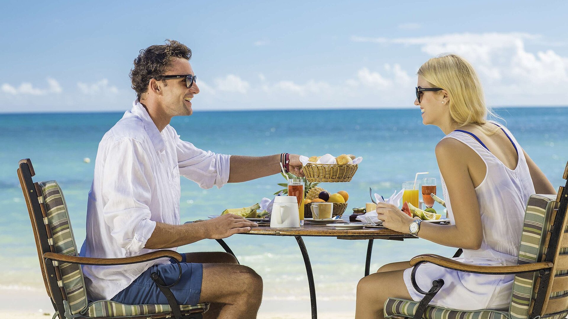 Couple prenant un petit-déjeuner détendu sur la plage avec vue sur la mer par une journée ensoleillée