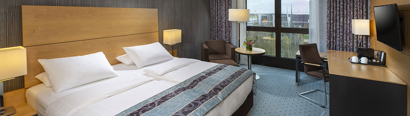 Chambre supérieure moderne au Maritim Hotel Düsseldorf avec grand lit, bureau et vue sur la ville.