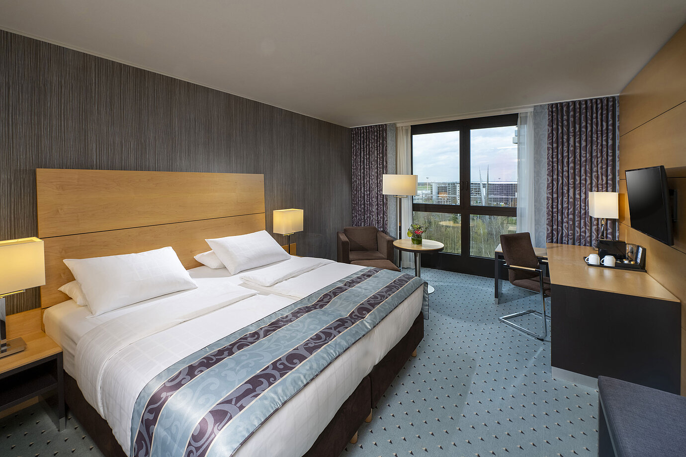 Chambre supérieure moderne au Maritim Hotel Düsseldorf avec grand lit, bureau et vue sur la ville.