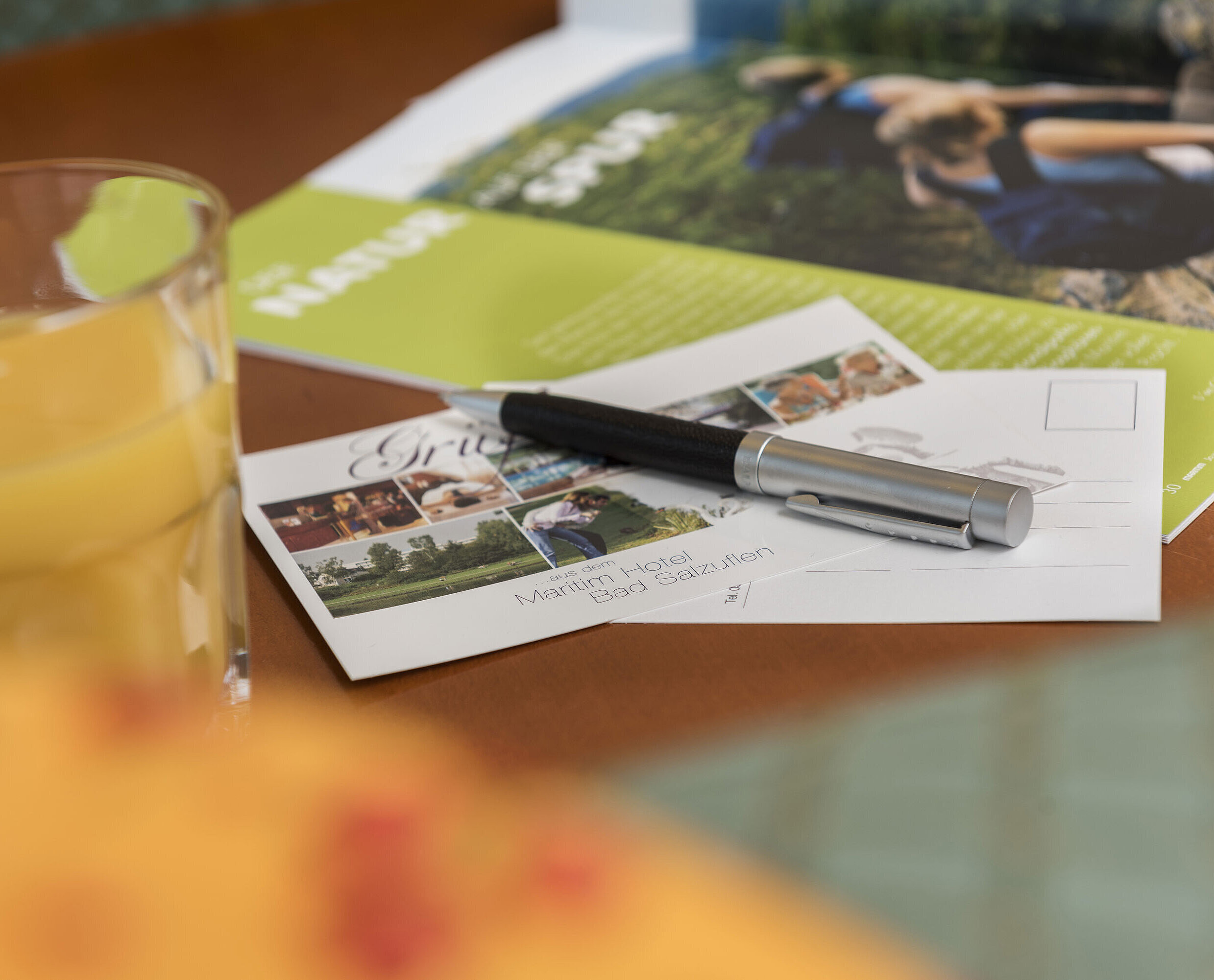 Détail de la chambre Table avec carte postale du Maritim Hotel Bad Salzuflen, stylo, jus et brochure