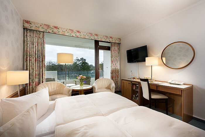 Chambre classique au Maritim Seehotel Timmendorfer Strand avec balcon, lit double, coin salon, TV et bureau.
