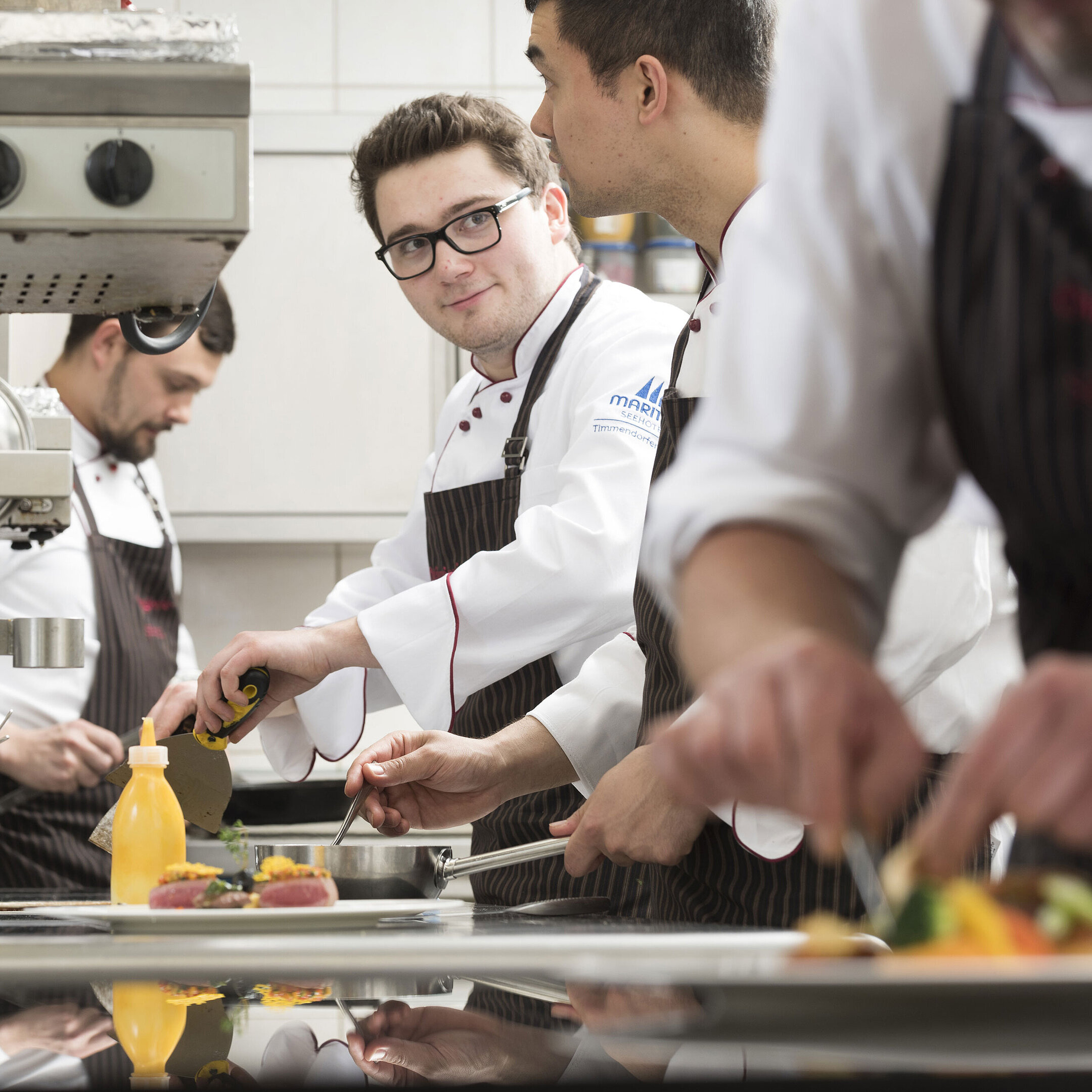 Chefs preparing gourmet dishes in the kitchen of the Orangerie at Maritim Seehotel Timmendorfer Strand.