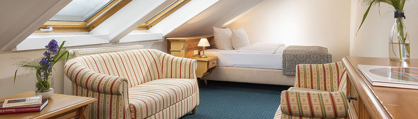 Family suite Cosy attic room with skylights, sofa and armchair at Maritim Hotel Titisee