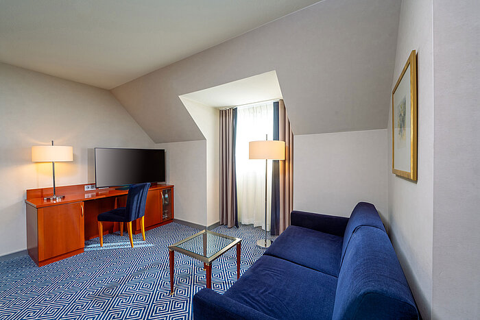 Habitación familiar Classic Zona de estar de la habitación familiar Classic del Maritim Hotel Würzburg con sofá cama y escritorio