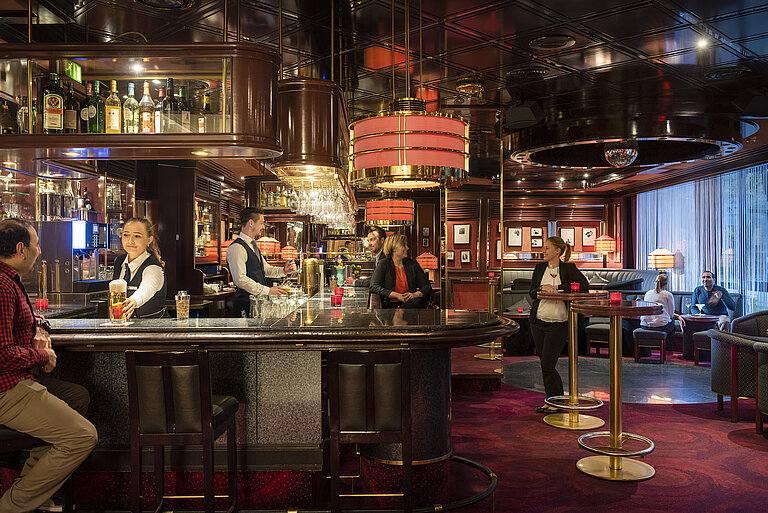 Gli ospiti gustano drink e un'atmosfera rilassata nella bar elegante del Maritim Hotel Bremen, serviti da personale cordiale.