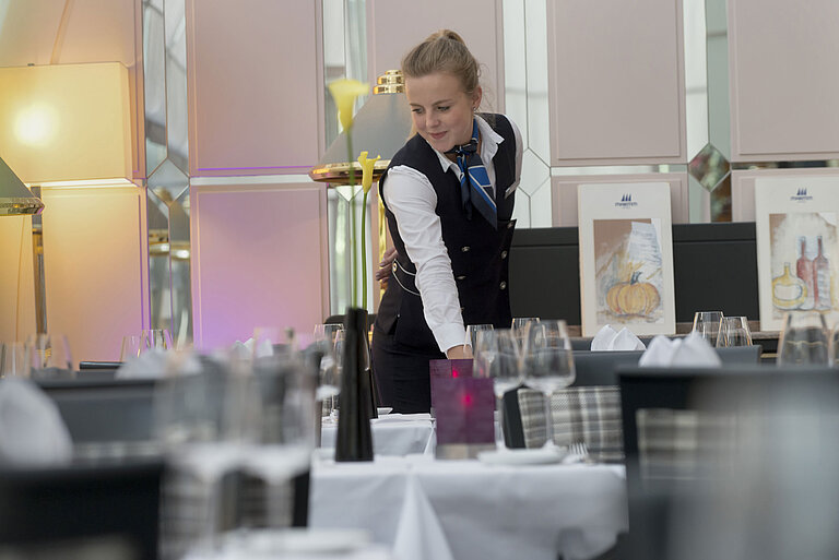 Cameriera apparecchia con stile il tavolo al ristorante del Maritim Hotel Monaco