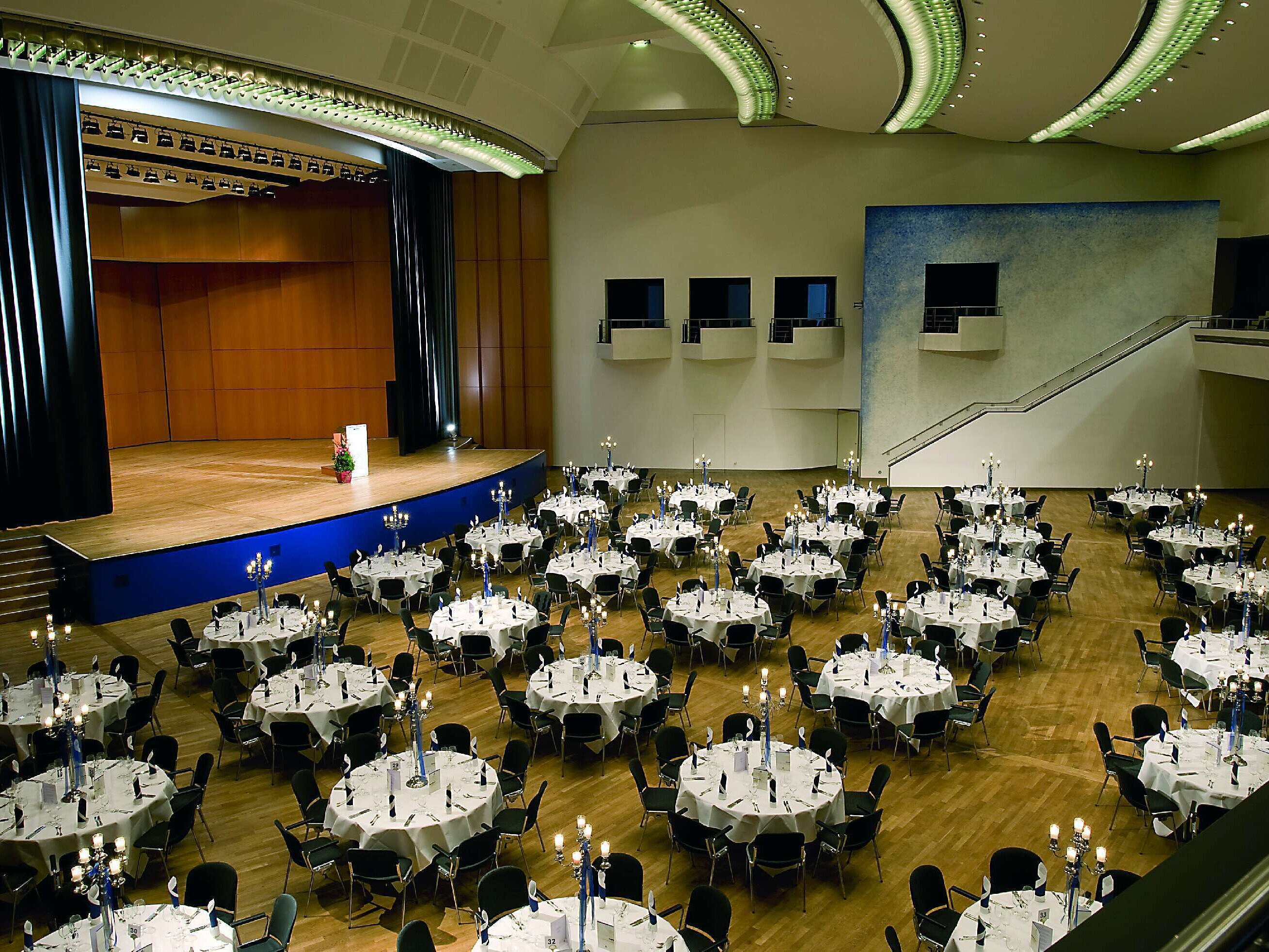 Grande salle d’événement au Maritim Hotel Ulm avec scène et tables rondes pour des fêtes élégantes