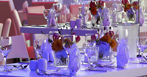 Close-up of elegantly set tables with floral arrangements in the event room at Maritim Hotel Dresden.