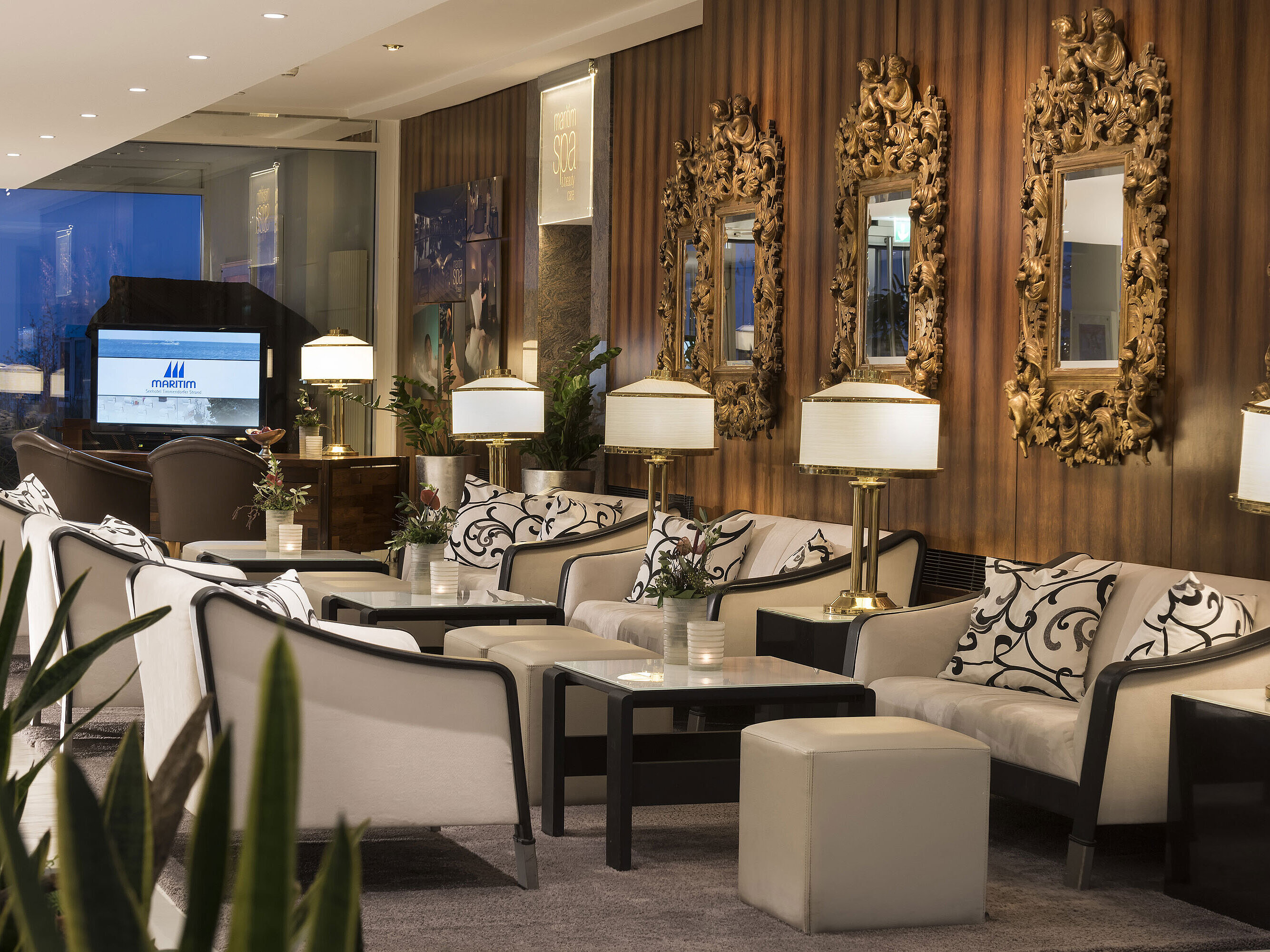 Lobby elegante con posti a sedere e specchi dorati al Maritim Seehotel Timmendorfer Strand.