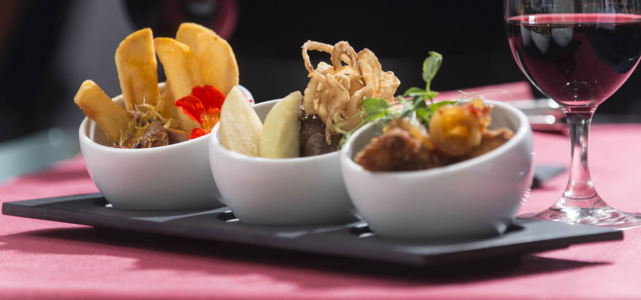Gros plan sur des tapas à l'hôtel Maritim proArte Berlin, avec un verre de vin rouge en arrière-plan.