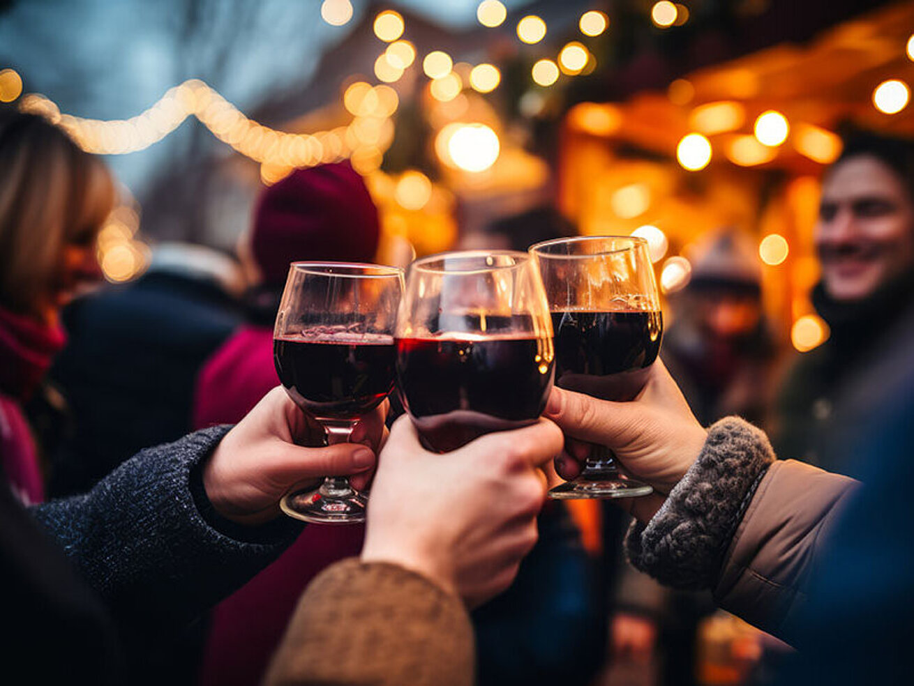 People clinking mugs of mulled wine at a Christmas market – festive atmosphere during the Advent season