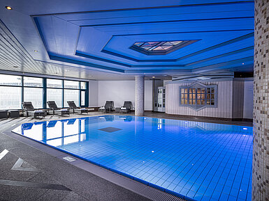 Indoor pool at Maritim Hotel Hannover with loungers and modern lighting.