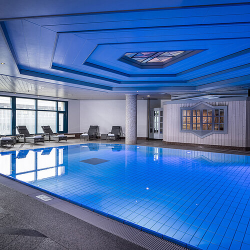 Piscina cubierta en Maritim Hotel Hannover con tumbonas e iluminación moderna.