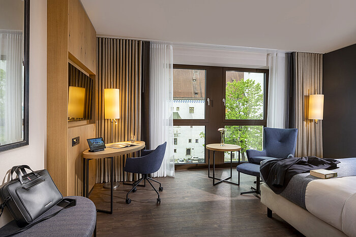 Habitación moderna del Maritim Hotel Ingolstadt con escritorio y vista a la ciudad.