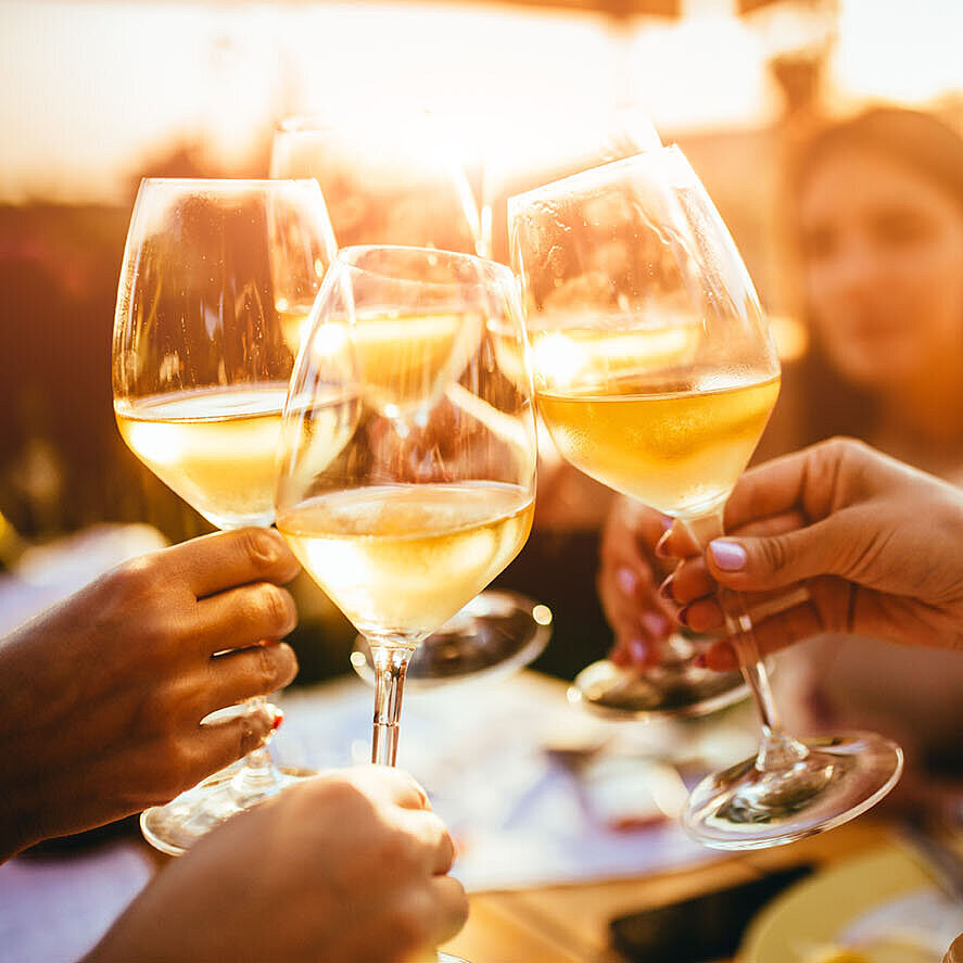 ©minastefanovic - AdobeStock.com Friends clinking wine glasses while enjoying an evening together at sunset