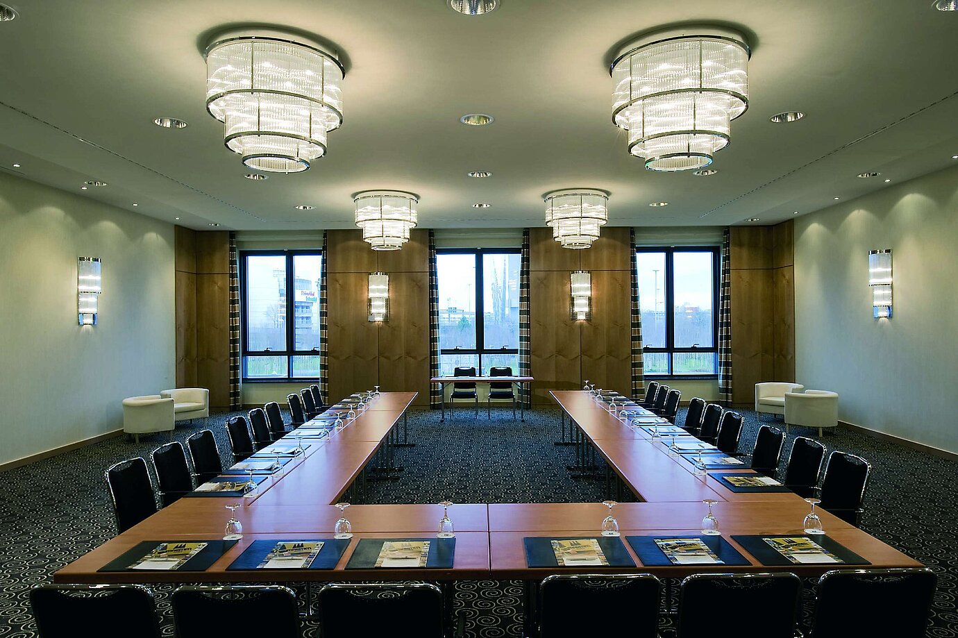 Modern conference room at Maritim Hotel Düsseldorf with U-shaped seating, large windows, and elegant lighting.
