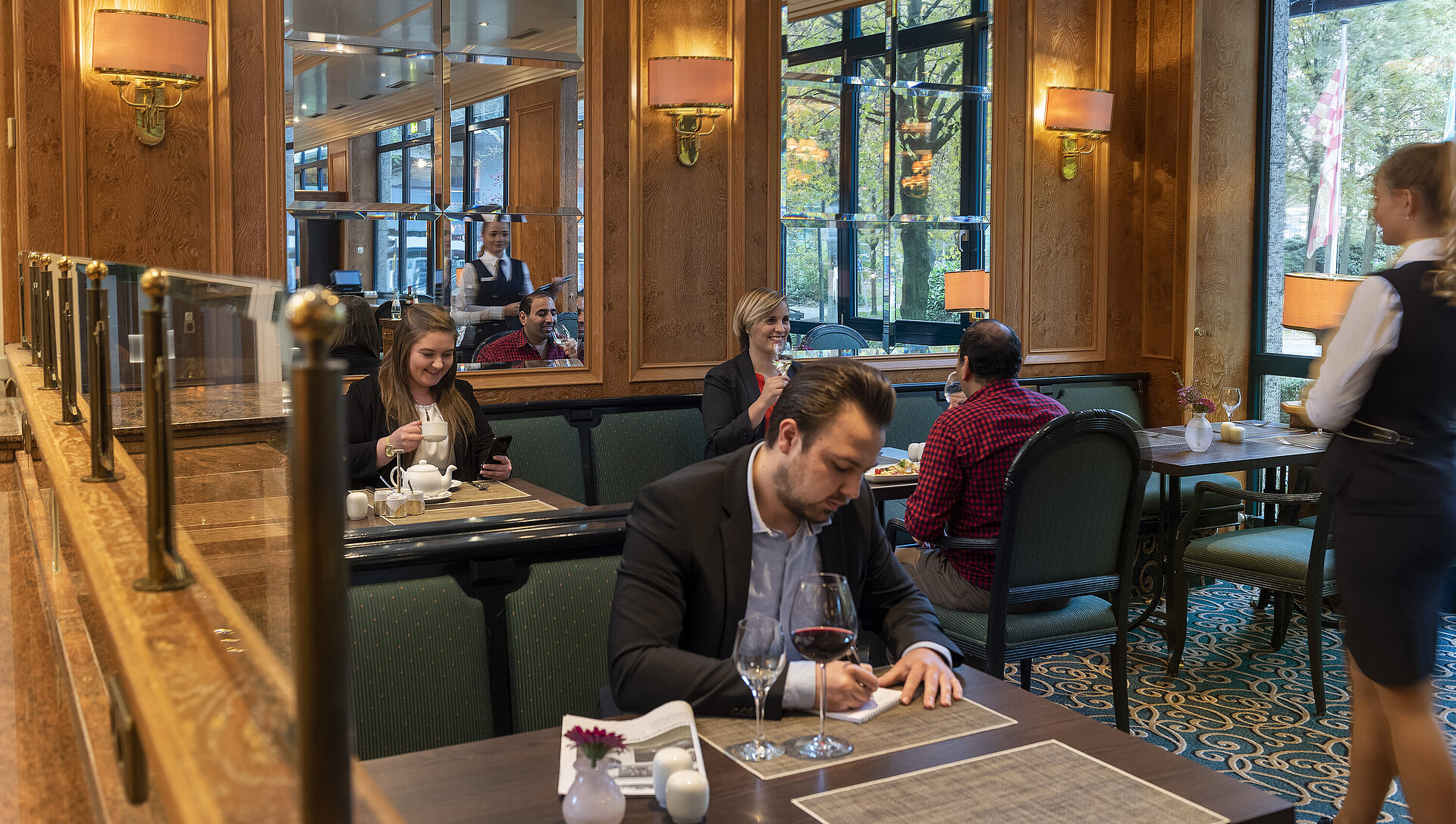 Gli ospiti si godono il pasto e si rilassano nella brasserie elegante del Maritim Hotel Bremen con un servizio cordiale.