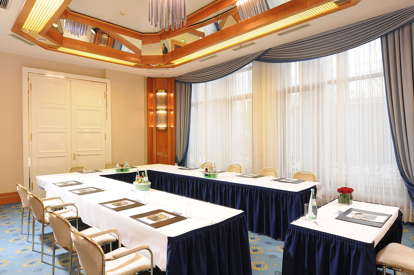 Salon Hamburg en el Maritim Hotel Magdeburg con asientos en U, cortinas elegantes y luz natural para reuniones exitosas.
