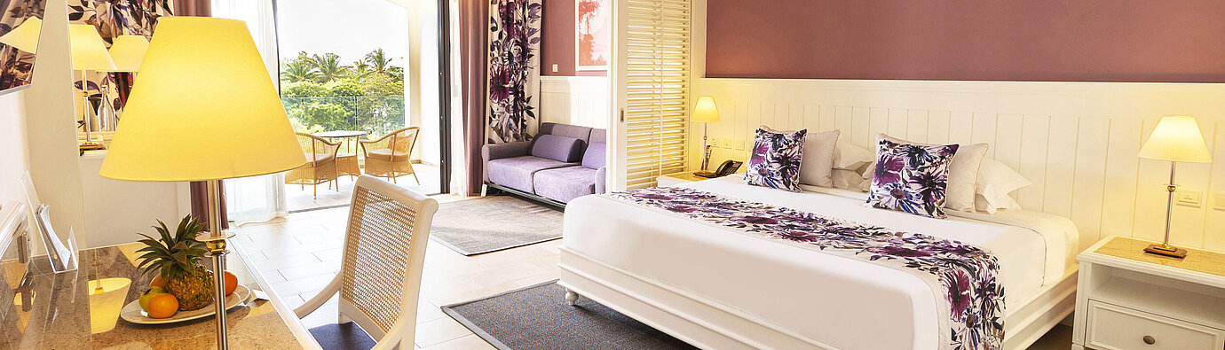 Habitación con cama king-size, muebles elegantes y acceso a la terraza con vista al mar