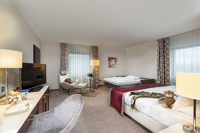 Camera familiare Comfort al Maritim Hotel Bonn con divano letto, mobili moderni e decorazioni eleganti per un soggiorno rilassante.