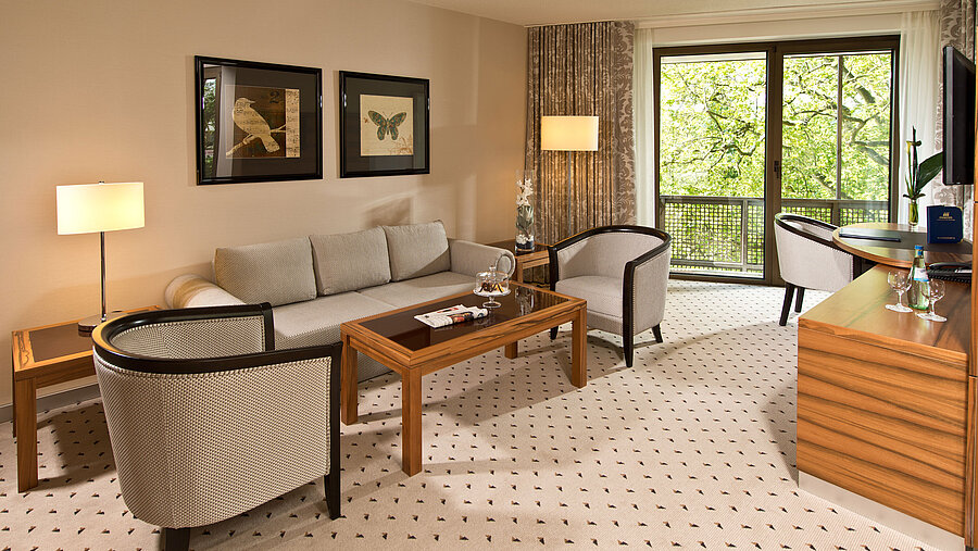 Área de estar acogedora de la suite en el Hotel Maritim Bad Homburg con zona de asientos elegante y balcón.