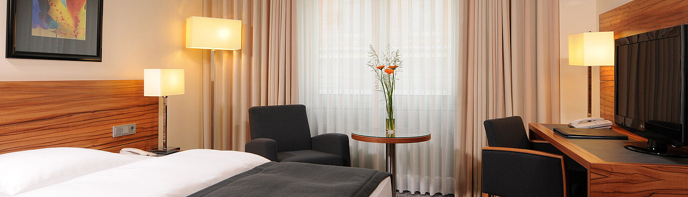 Camera singola moderna con letto, poltrone e grande finestra al Maritim Hotel Monaco