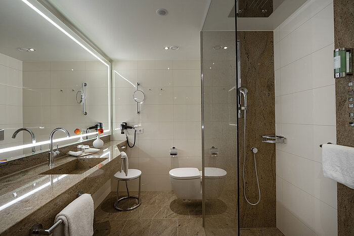 Baño moderno en el Maritim Hotel Ingolstadt con ducha de cristal y espejo grande.