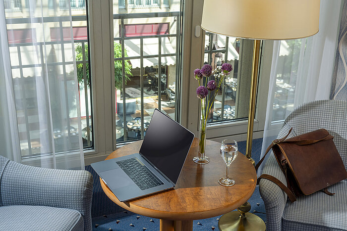 Camera Classic presso l'Hotel Maritim Colonia con laptop, bicchiere d'acqua, borsa in pelle e fiori in vaso.