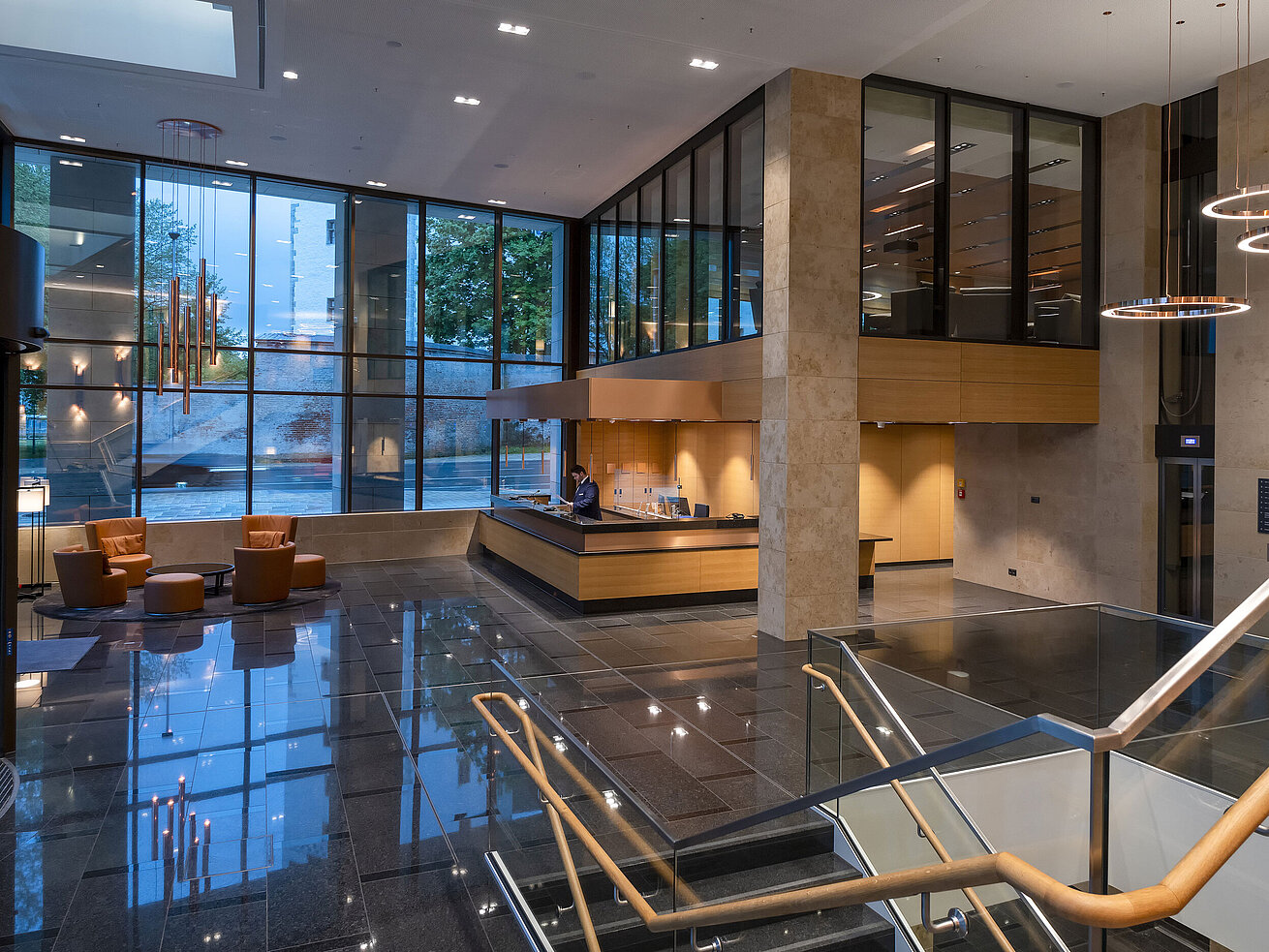 The modern lobby of Maritim Hotel Ingolstadt with high glass windows, reception, and cozy seating areas.