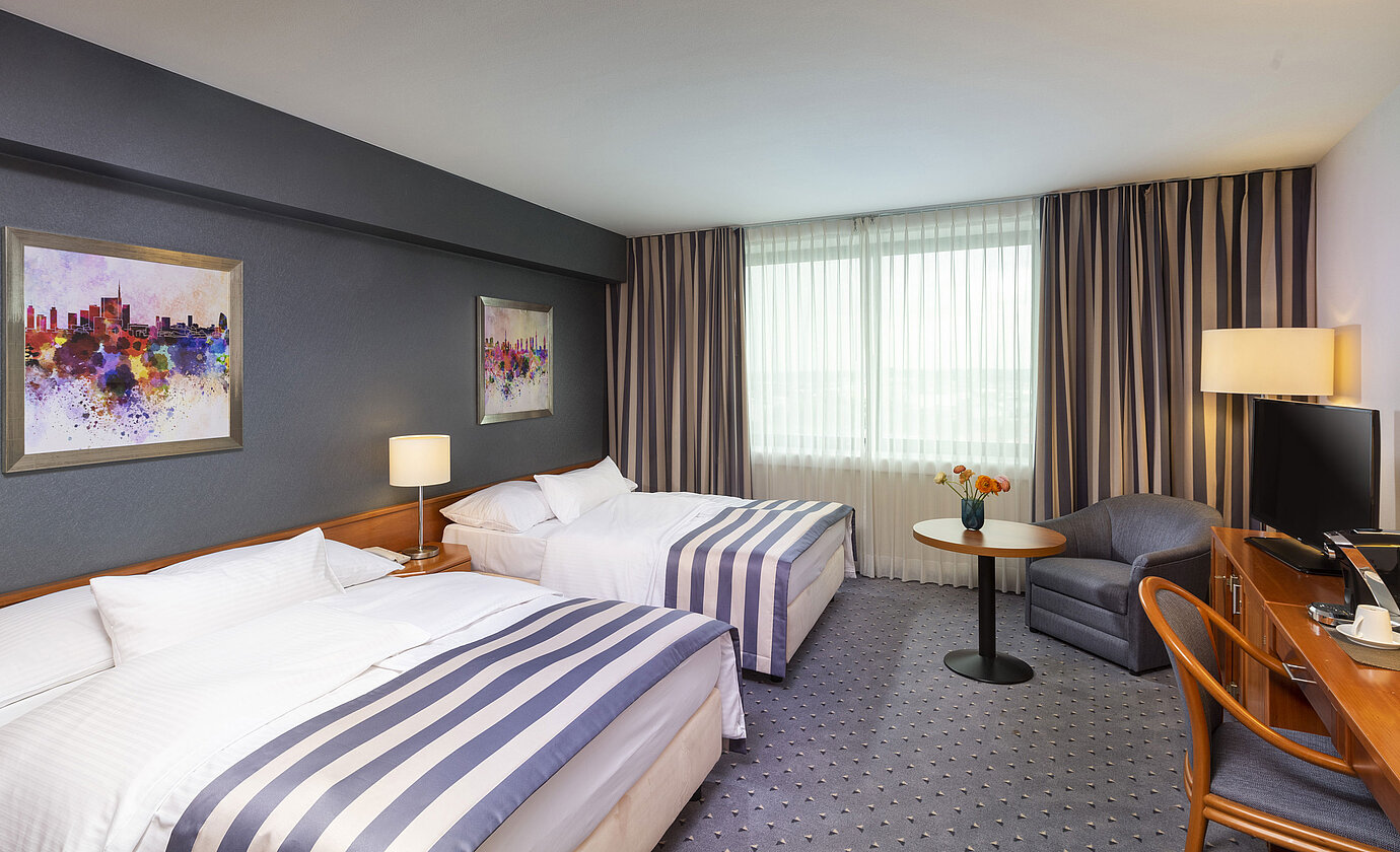 Camera familiare al Maritim Hotel Ulm con due letti singoli, TV e zona relax