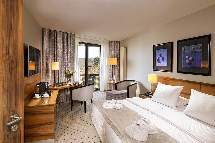 Chambre confort à l'hôtel Maritim Bad Homburg avec balcon, design lumineux et coin salon confortable.