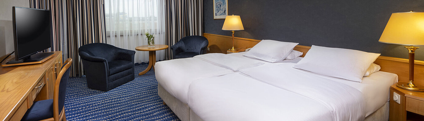 Comfort double room with seating area, desk, and modern artwork on the wall