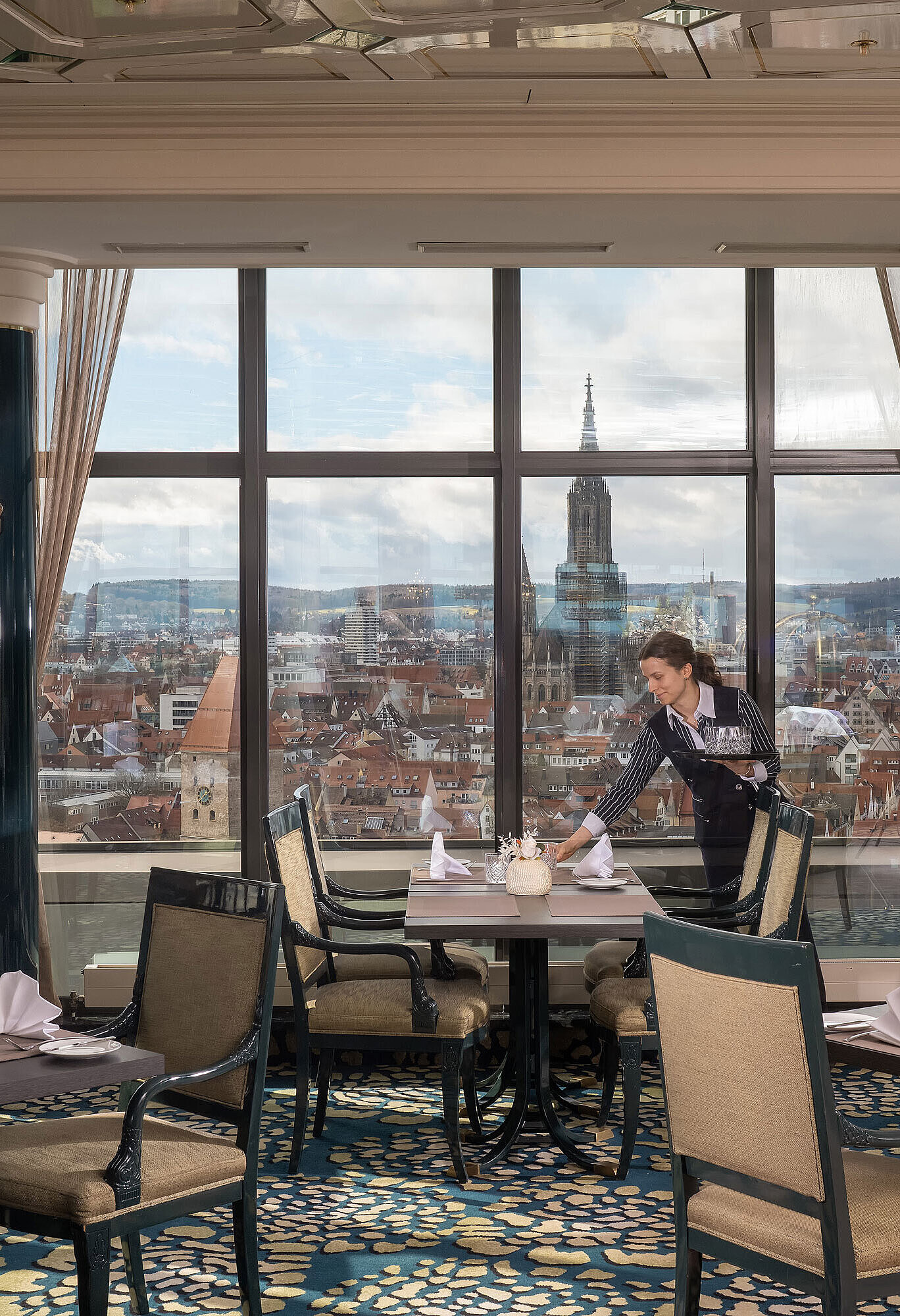 Restaurant au Maritim Hotel Ulm avec tables dressées, grandes baies vitrées et vue sur Ulm et la cathédrale d’Ulm
