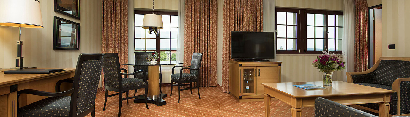 Junior Suite al Maritim Hotel Dresden con area salotto elegante, grande scrivania e design moderno.