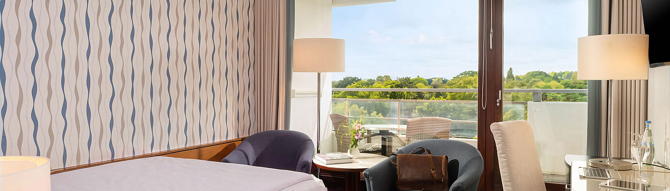 Camera Classic Queen con letto queen-size, area salotto, scrivania e ampia finestra con vista sul verde