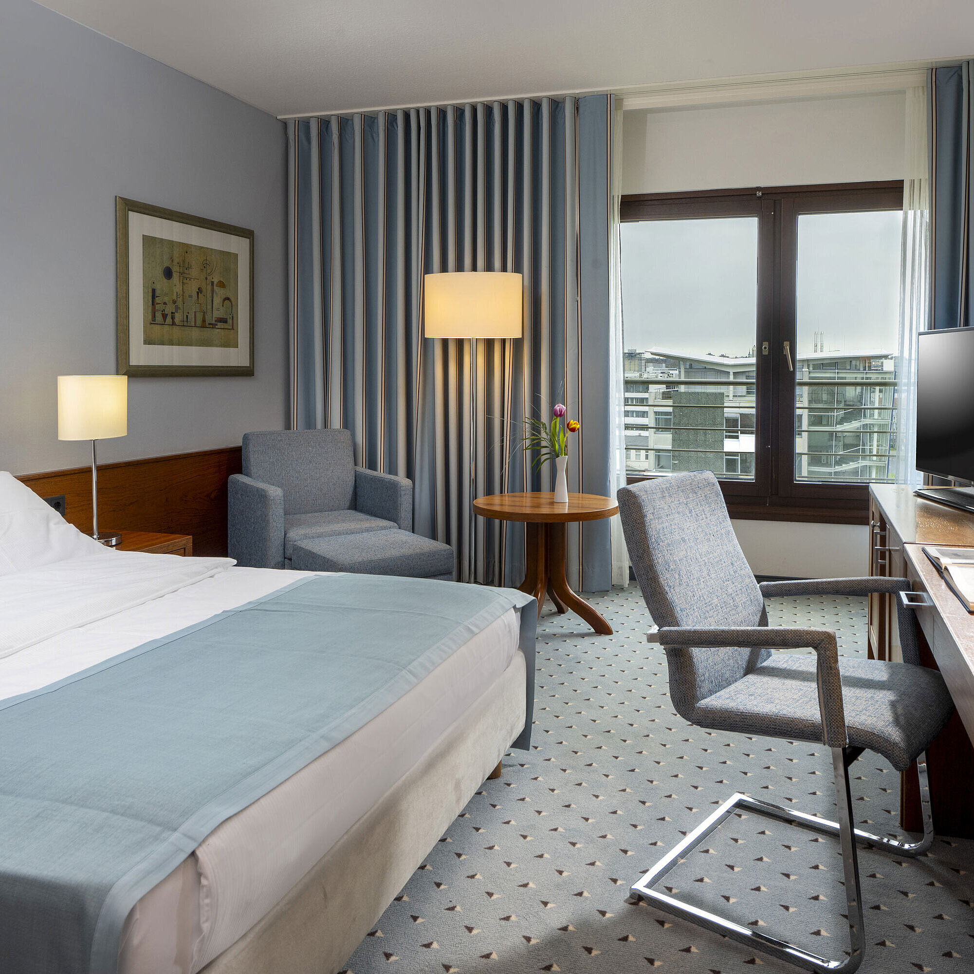 Chambre Comfort Chambre double confort à l'hôtel Maritim Darmstadt avec coin salon confortable, bureau moderne et vue sur la ville.