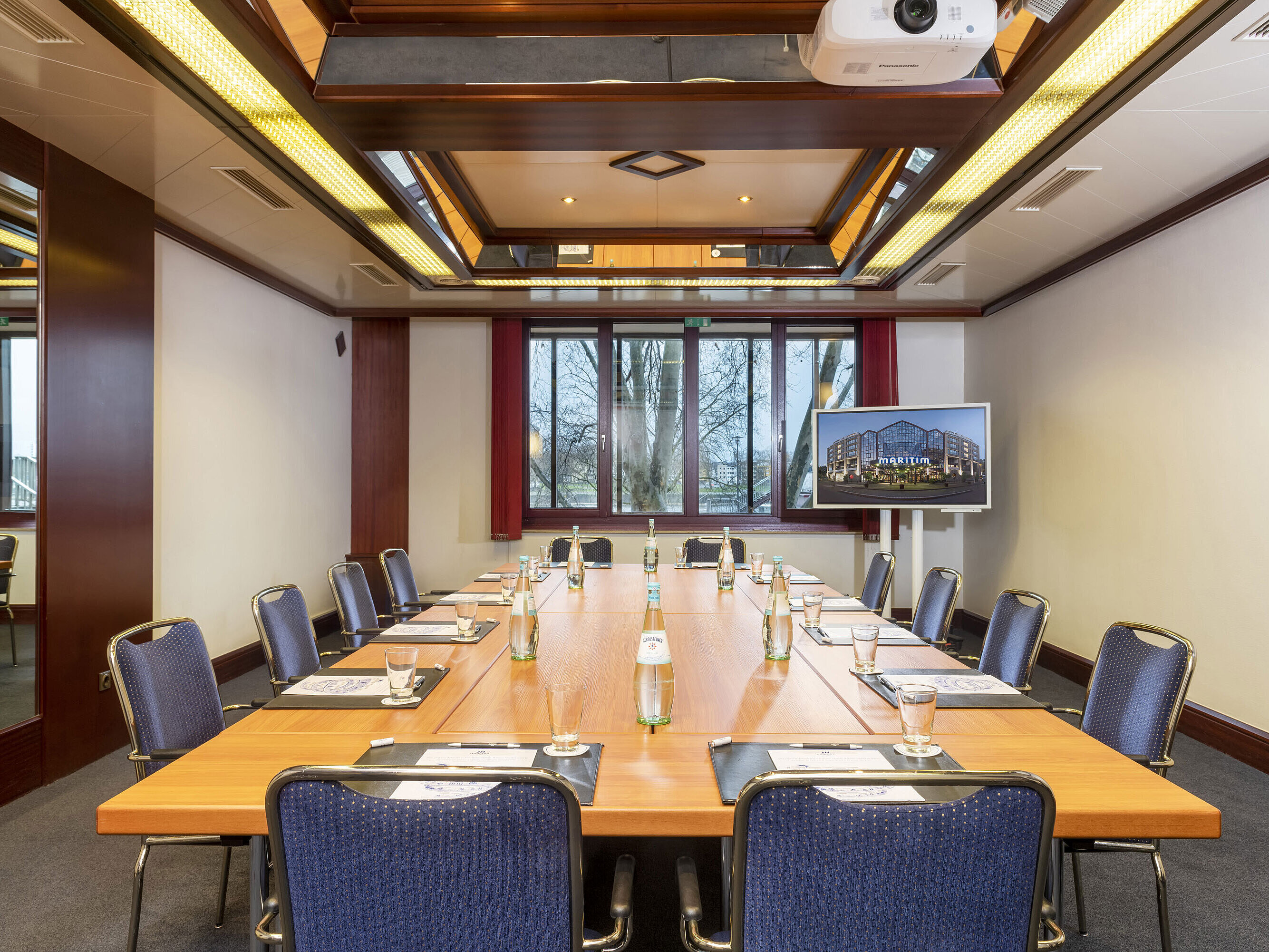 Salón Loreley, una moderna sala de conferencias con disposición cuadrada, proyector y pantalla para presentaciones.