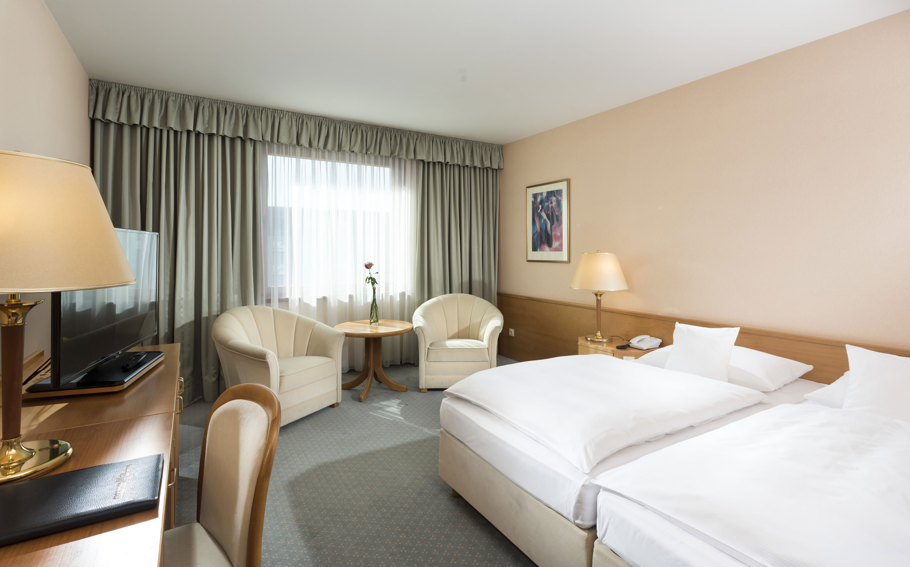 Bright hotel room with two beds, seating area and large window at Maritim Hotel Magdeburg